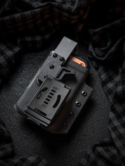 Rear view of the black Single Skeleton Window phone case with belt clip, shown with a smartphone inside on a dark plaid fabric background.