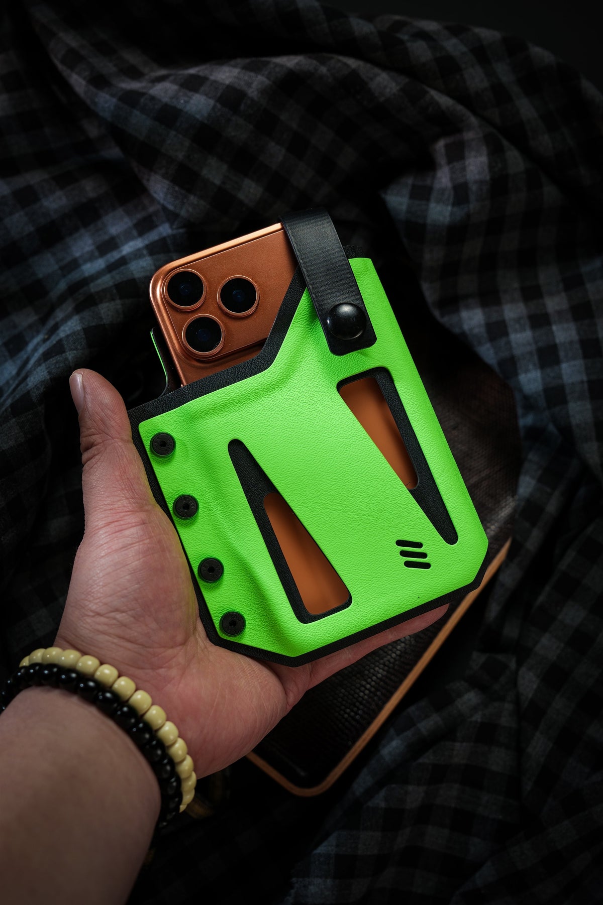 Handheld view of the neon green Skeleton Frame phone case for iPhone 17 Pro and iPhone 17 Pro Max with an orange smartphone inside.