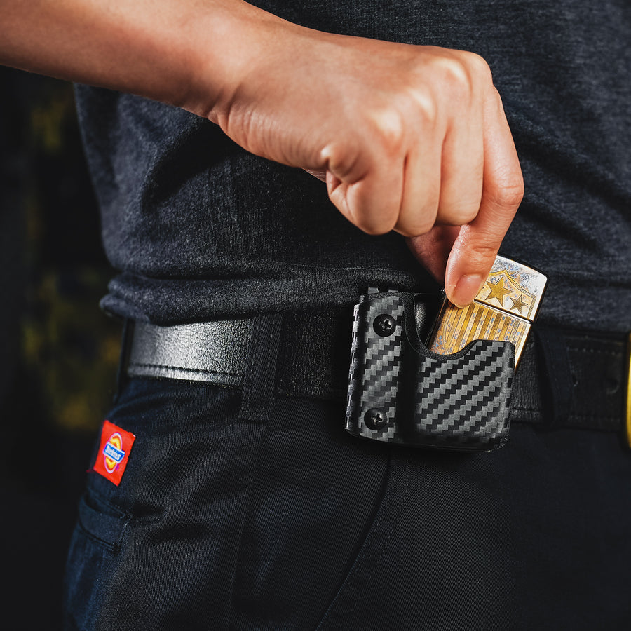 Lifestyle image showing the carbon fiber TX2 KYDEX EDC Zippo lighter sheath clipped to a belt while removing the lighter.