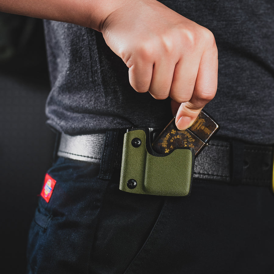 Lifestyle image showing the green TX2 KYDEX EDC Zippo lighter sheath clipped to a belt while removing the lighter.