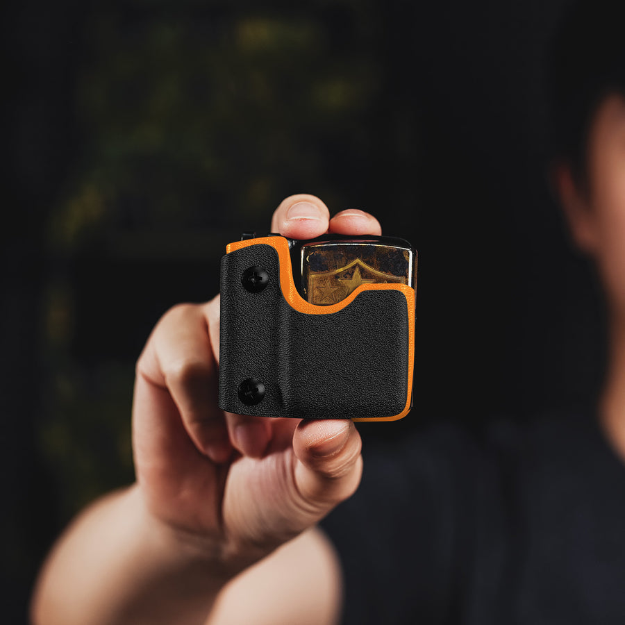 Handheld lifestyle image of the orange TX2 KYDEX EDC Zippo lighter sheath with a lighter inserted.