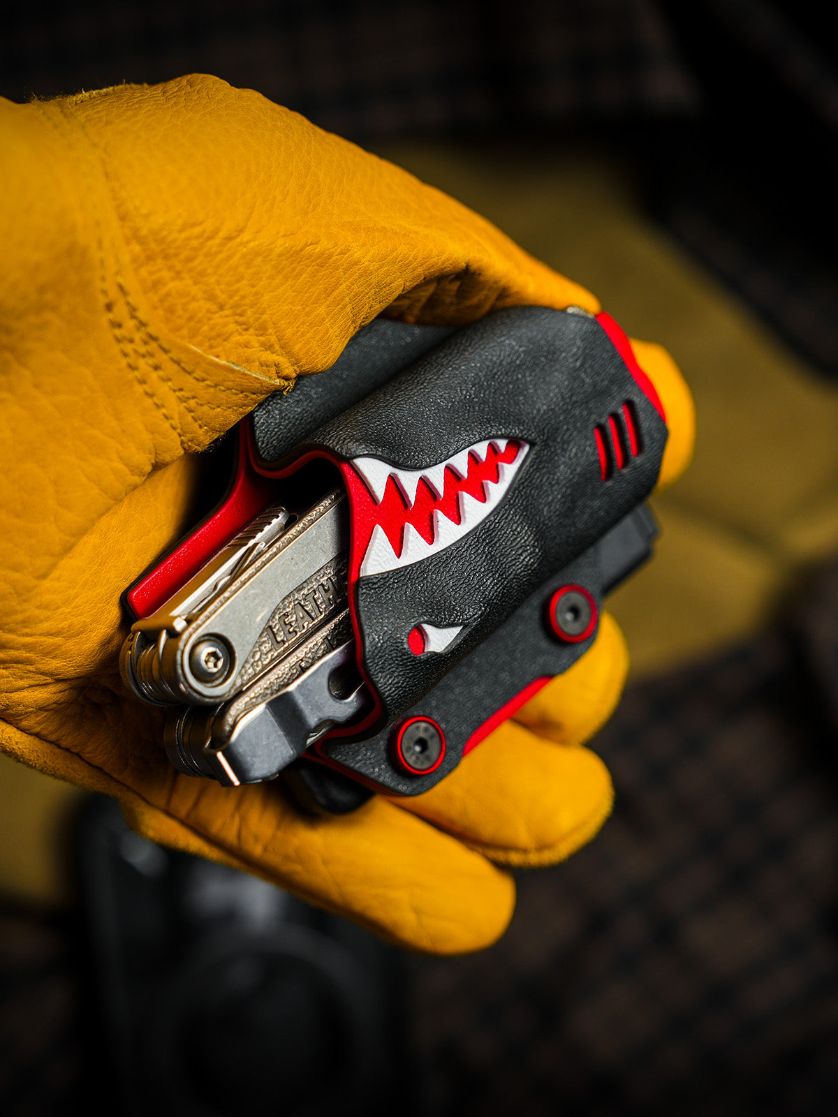 Angled handheld view of the shark-style TX15 multi-tool sheath for Leatherman Charge with the tool partially exposed.