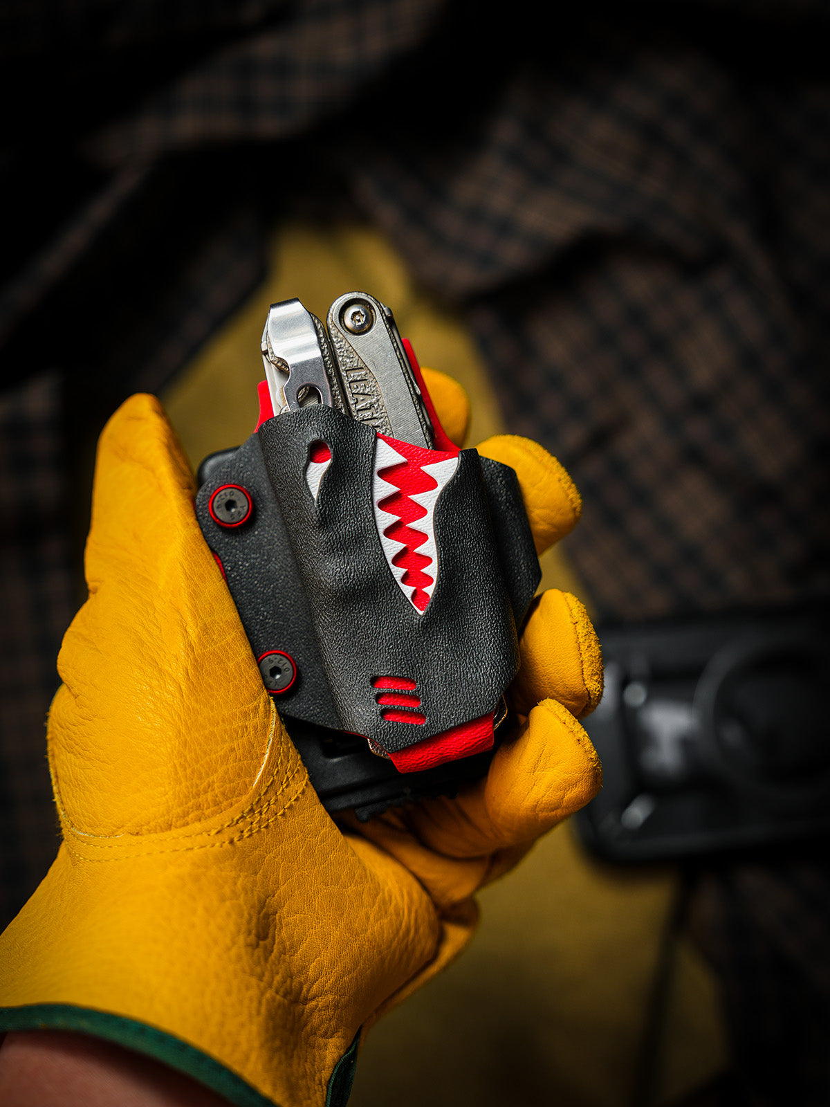 Shark-style TX15 multi-tool sheath for Leatherman Charge with belt clip, shown upright in a gloved hand.