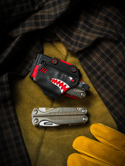 Shark-style TX15 multi-tool sheath for Leatherman Charge with belt clip, displayed with the tool on a fabric surface.