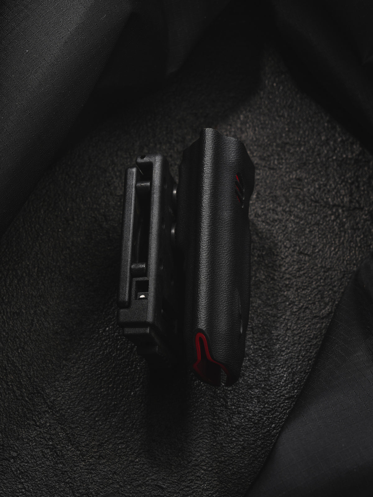 TACTICALGEEK TX9 flashlight sheath for Nitecore EDC27 slim side profile on a dark textured background.