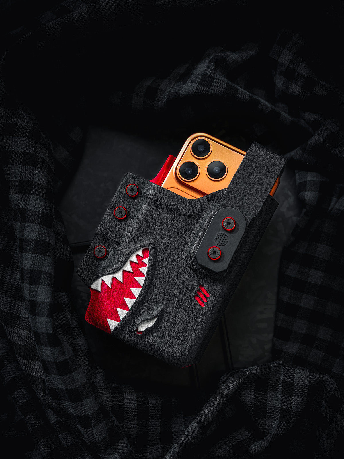 Black and red shark-style TACTICALGEEK TG EDC KYDEX phone sheath holding an orange iPhone 17 Pro, front product display.