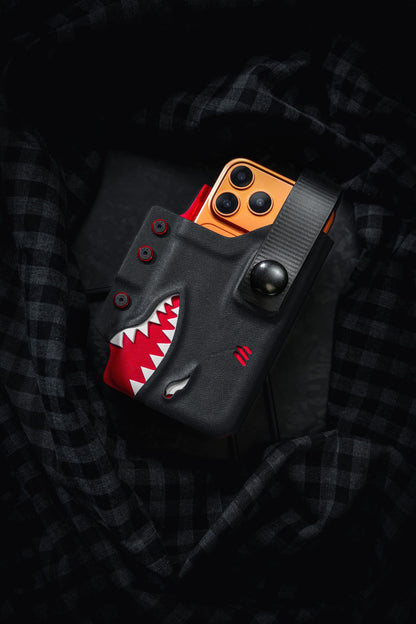 Black and red TACTICALGEEK TG EDC KYDEX shark phone sheath for iPhone 17 Pro and iPhone 17 Pro Max with snap strap closure.