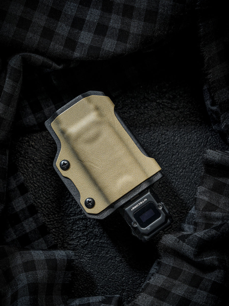 Sand-colored TX10 Flashlight Sheath holding a Nitecore EDC29 flashlight, shown on a dark plaid fabric background.