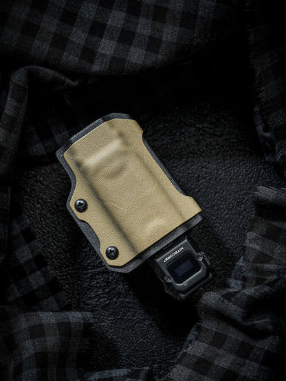 Sand-colored TX10 Flashlight Sheath holding a Nitecore EDC29 flashlight, shown on a dark plaid fabric background.