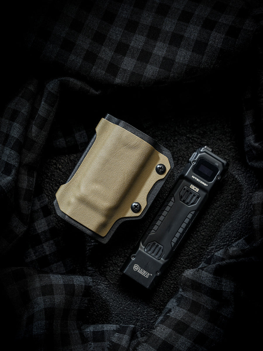 Flat lay of the sand-colored TX10 Flashlight Sheath placed beside a Nitecore EDC29 flashlight on a dark fabric background.