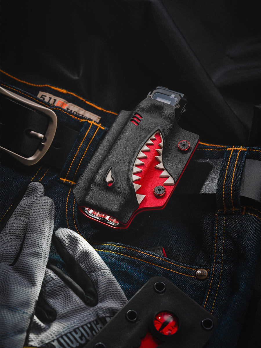 Shark-style TX10 Flashlight Sheath clipped to a belt on denim jeans, holding a Nitecore EDC29 flashlight.