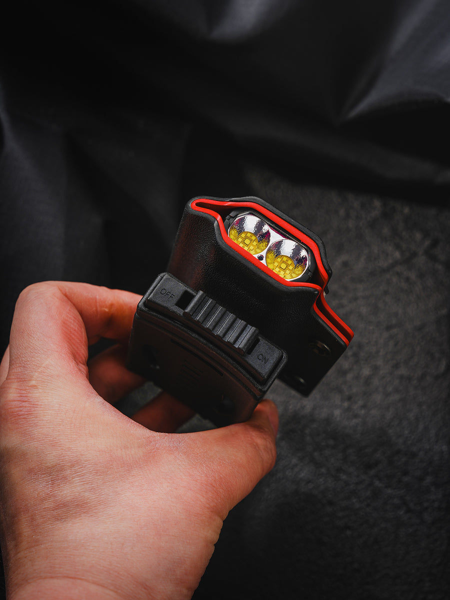 Handheld close-up of the shark-style TX10 Flashlight Sheath showing the flashlight lens and bottom switch detail.