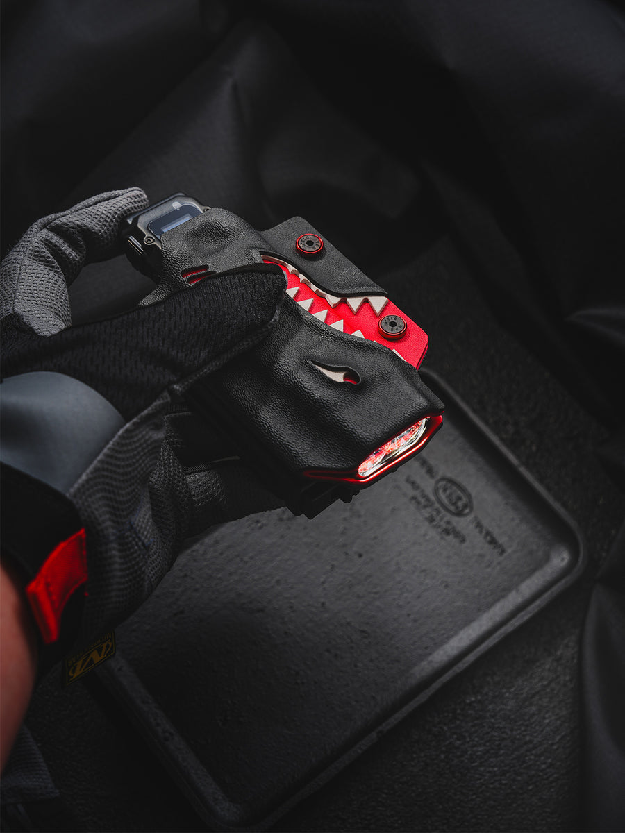 Gloved hand holding the shark-style TX10 Flashlight Sheath with a Nitecore EDC29 flashlight inserted.