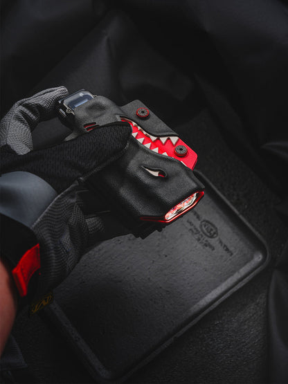 Gloved hand holding the shark-style TX10 Flashlight Sheath with a Nitecore EDC29 flashlight inserted.