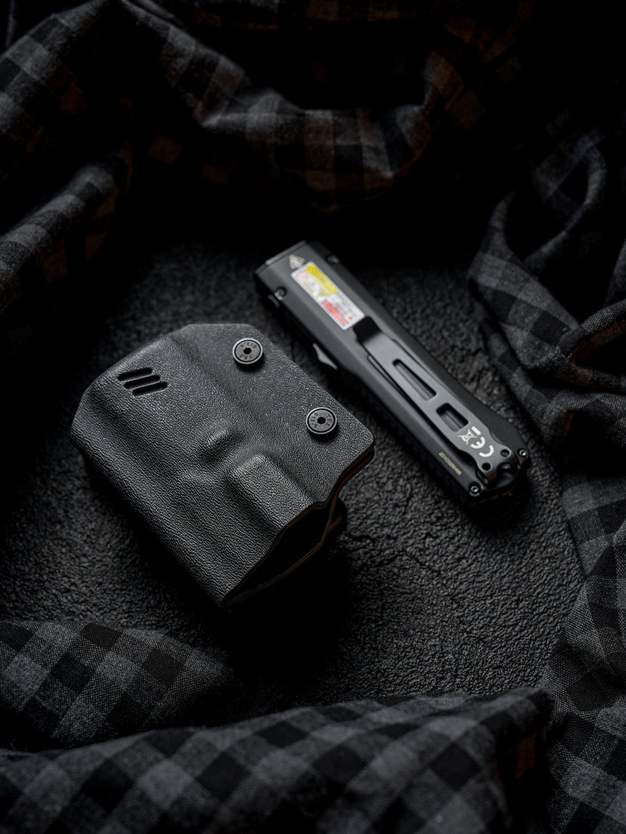 Angled flat lay view of the black TX17 flashlight sheath for Nitecore EDC17 with the flashlight placed beside it on a dark fabric background.
