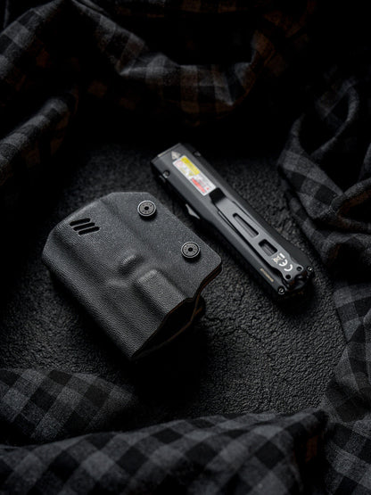Angled flat lay view of the black TX17 flashlight sheath for Nitecore EDC17 with the flashlight placed beside it on a dark fabric background.