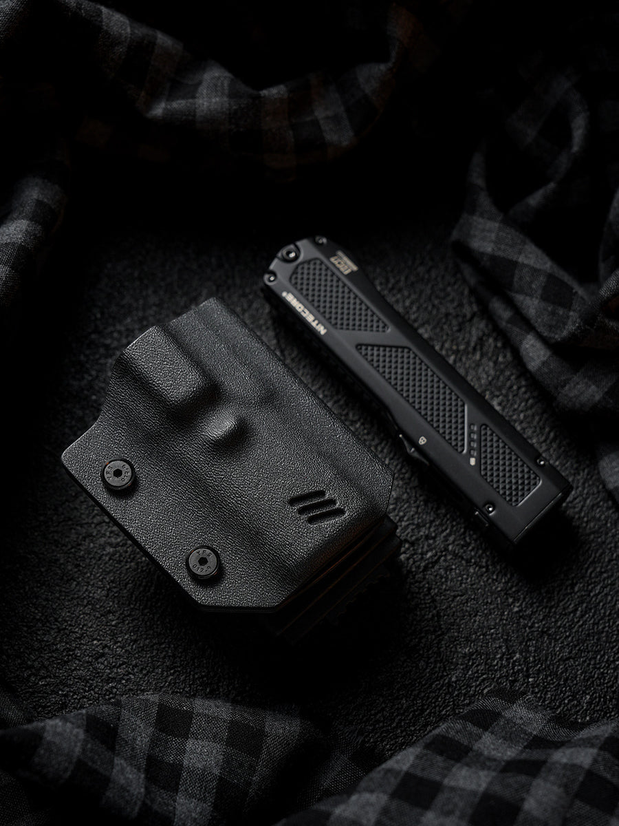Flat lay of the black TX17 flashlight sheath for Nitecore EDC17 placed beside the flashlight on a dark textured background.