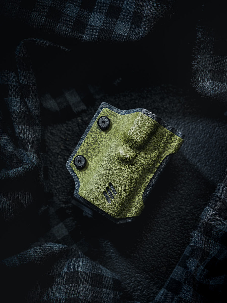 Front view of the olive green TX17 flashlight sheath for Nitecore EDC17 displayed alone on a dark plaid fabric background.