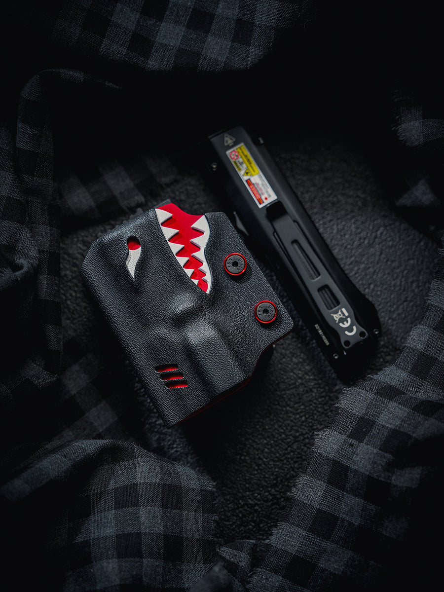Flat lay of the TX17 shark-style flashlight sheath and Nitecore EDC17 flashlight placed separately on a dark textured fabric background.
