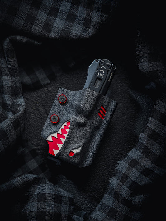 Front view of the TX17 shark-style flashlight sheath for Nitecore EDC17, shown with the flashlight inserted in the sheath on a dark plaid fabric background.