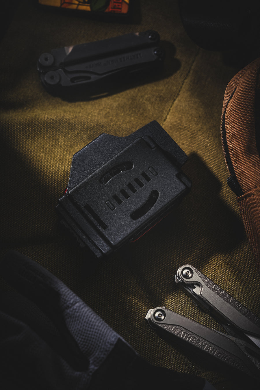Rear view of the TX19 sheath for Leatherman Surge, highlighting the black belt clip on the back with EDC gear nearby.