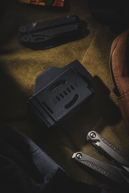 Rear view of the TX19 sheath for Leatherman Surge, highlighting the black belt clip on the back with EDC gear nearby.