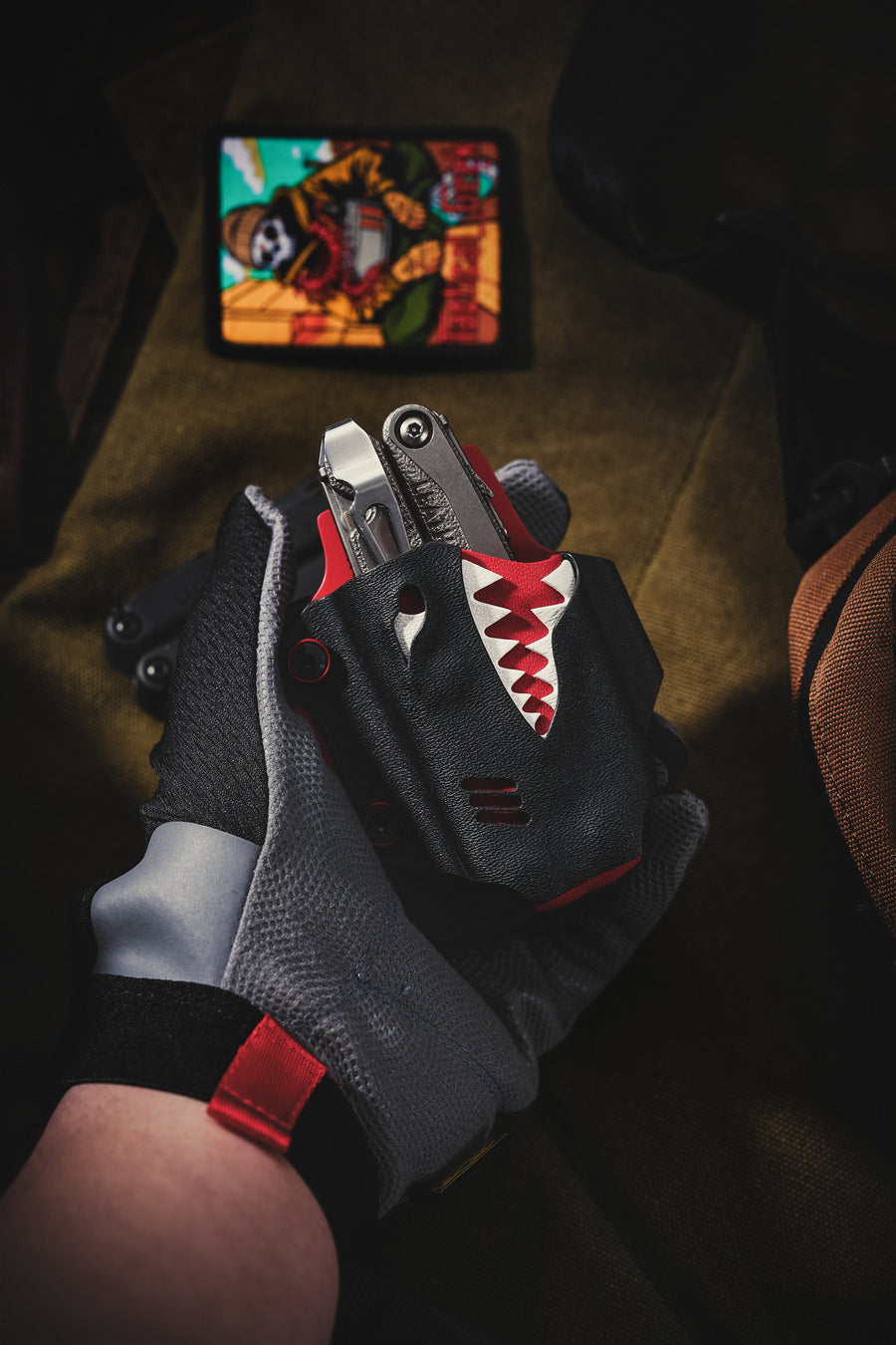 TX19 shark-style sheath for Leatherman Surge with the multi-tool partially inserted, held in hand against a dark outdoor-themed background.