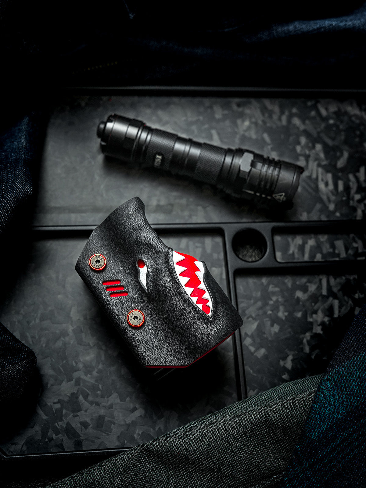 Flat lay front view of the TX22 shark-style flashlight sheath for Nitecore P20ix placed beside the flashlight on a dark textured background.