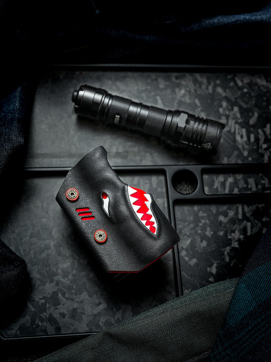 Flat lay front view of the TX22 shark-style flashlight sheath for Nitecore P20ix placed beside the flashlight on a dark textured background.