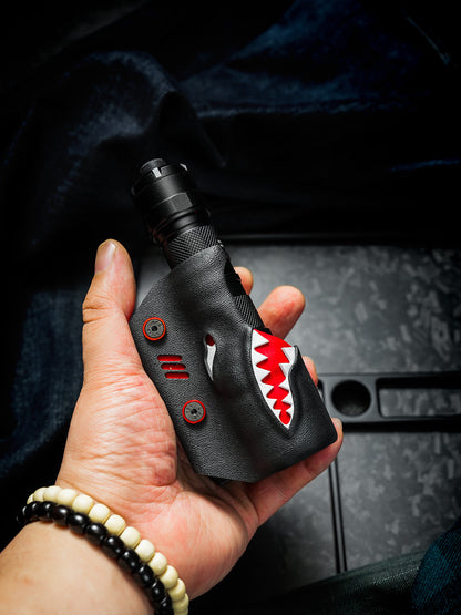 Hand holding the TX22 shark-style flashlight sheath with a Nitecore P20ix inserted, featuring the black and red shark-inspired design and belt clip.
