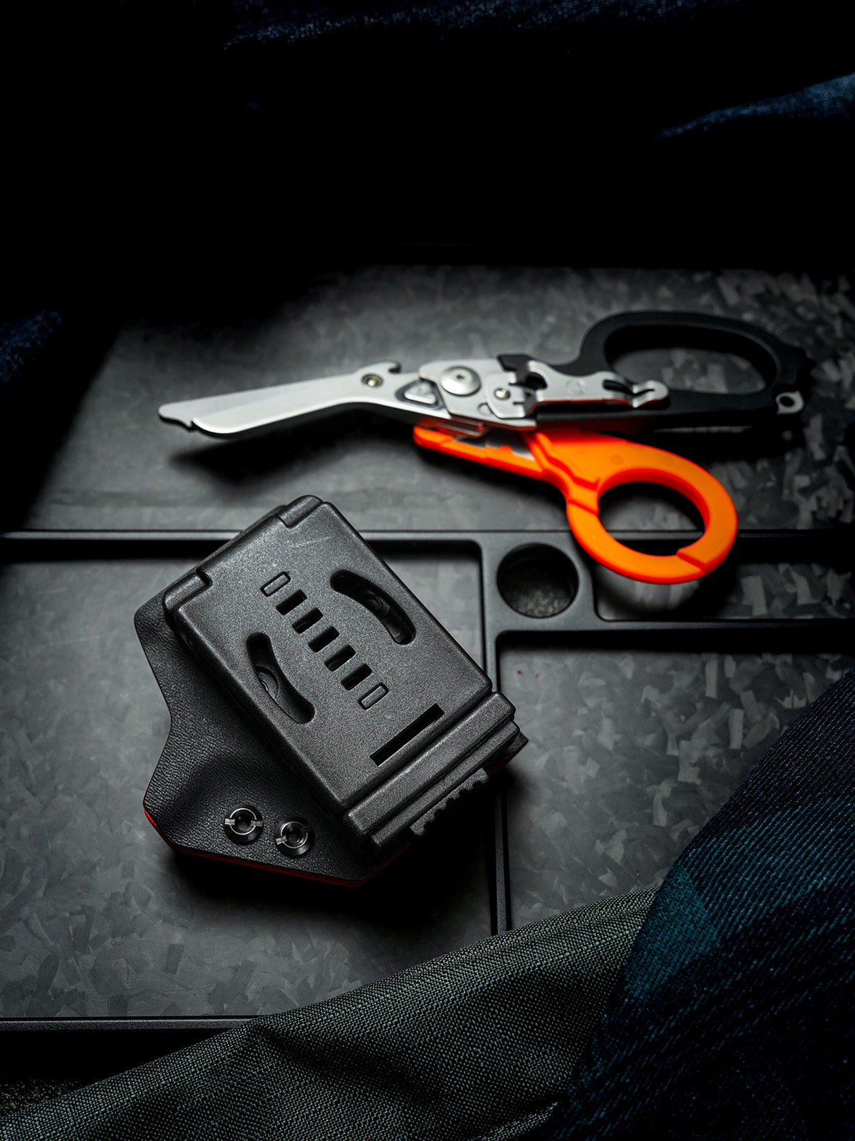 Rear view of the TX24 shark-shaped sheath for Leatherman Raptor featuring a black belt clip, with rescue shears in the background.