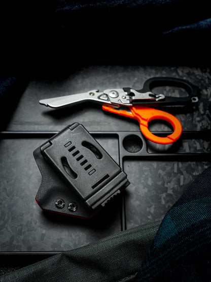 Rear view of the TX24 shark-shaped sheath for Leatherman Raptor featuring a black belt clip, with rescue shears in the background.