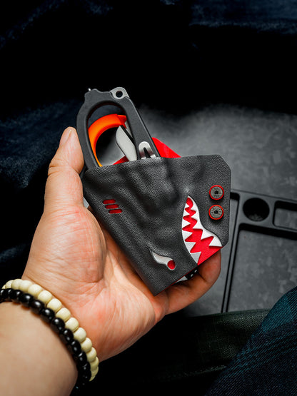 Hand holding the shark-shaped TX24 multi-tool sheath for Leatherman Raptor with the rescue shears stored inside.