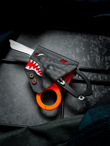 Shark-style TX24 sheath holding Leatherman Raptor rescue shears, with the handle and tool partially exposed.